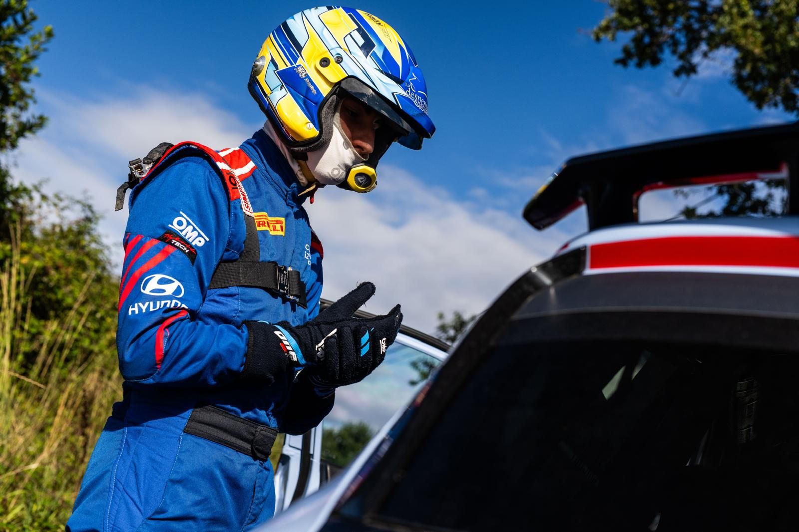 Alejandro Medín con el casco y el mono de Hyundai junto a su coche de rally